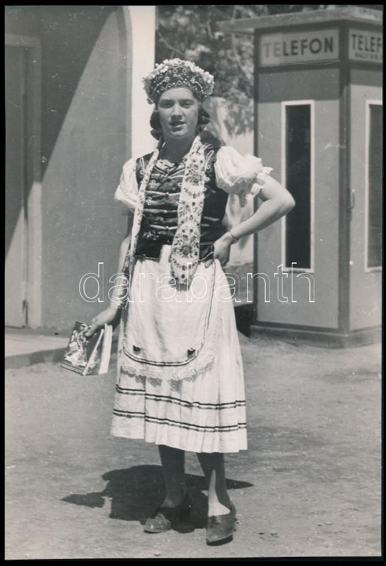 cca 1936 Budapesti Nemzetközi Vásáron Globus reklámkatalógust osztogat a magyaros népviseletbe öltözött leány, Reich Péter Cornel pecsétjével jelzett vintage fotó, 29,5x20,2 cm