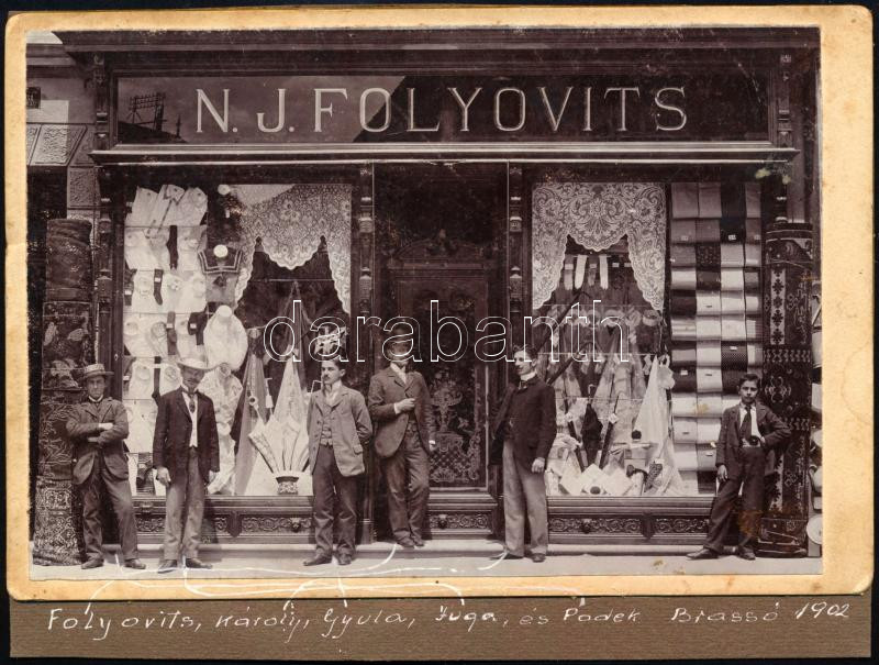 1902 Brassó, N. J. Folyovits divatárú üzletének kirakata és bolt személyzete és vásárlói. feliratozott kabinetfotó kartonra ragasztva 16x11   1902 Brassó, N. J. Folyovits' fashion store window and store staff and customers. signed cabinet photo glued to cardboard 16x11 cm