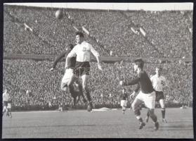 1955 Kocsis Sándor fejjel továbbít, Czibor már várja a labdát a 100. magyar-osztrák mérkőzésen, 1955. október 16-án a Népstadionban. A vége 6:1. Pecséttel, jelzett, feliratozott sajtófotó, 12x18cm