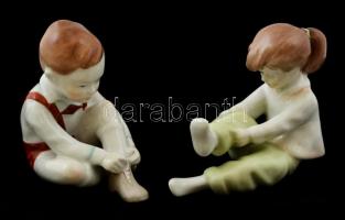 2 db Aquincumi figurális porcelán: cipőt fűző kisfiú + öltözködő kislány, kézzel festettek, jelzettek, apró kopásnyomokkal, m: 11 cm