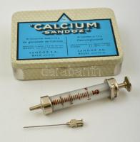 1972 Injekciós fecskendő, eredeti dobozában + injekciós tűk (2 db) + csavaros tetejű (bakelit) injekciós fiola Calcium Sandoz fém dobozban