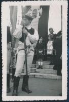 cca 1930 Népviseletes fiatalember, címeres országzászlóval, fotó, 7,5×11 cm