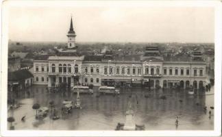 1942 Óbecse, Stari Becej; községháza, Szent István tér eső után, MÁVAUT autóbuszok, Hubet Izidor, Janek Testvérek, Bata cipő és fodrászterem üzlete, piaci bódék. Radoszávlyevits kiadása / town hall, square after rain, shops, autobuses, market stalls + ÓBECSE-ÚJVERBÁSZ 408 mozgóposta