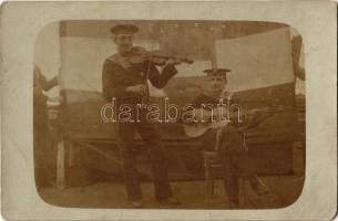 Osztrák-magyar matrózok hegedűvel és gitárral egy hadihajó fedélzetén, mögöttük a Cs. és Kir. Haditengerészet zászlóját tartják / WWI Austro-Hungarian Navy, K.u.K. Kriegsmarine, mariners playing the violin and the guitar, naval flag behind them. photo (fl)