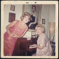 1965 A két díva - Gábor Zsazsa (1917-2016) kíséri zongorán Karády Katalint (1910-1990) kaliforniai otthonában, hátoldalon Gábor Zsazsa írásával, fotó, felületén törésnyomok, 8,5×8,5 cm