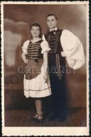 cca 1930-1940 Fiatal pár magyaros ruhában, fotólap Bäumler csepeli műterméből, 13,5×8,5 cm