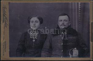 cca 1900 Soproni huszár és felesége, nyakában férje fényképével, keményhátú fotó Goetzloff Oszkár műterméből, 10,5×16,5 cm