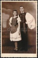 cca 1940 Fiatal pár magyaros ruhában, fotólap, Bäumler csepeli műterméből, 13,5×8,5 cm