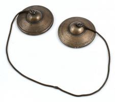 Tibeti szertartási cintányér (Tingsha), fém láncon, d: 7,8 cm, h. 55 cm. Két kisméretű, ám vastag öntött kis cintányér bőrszíjjal összekötve. A cintányérok anyaga bronz vagy 7 fém. Összeütve őket csodásan egyedülálló, a tingshára jellemző magas hangot adnak. Gyakran díszítik a tibeti 8 szerencsejellel, vagy mantrával, legtöbbször az Om Mani Padme Hung felirattal, így a hangszer mély, spirituáis jellegét erősítik. 