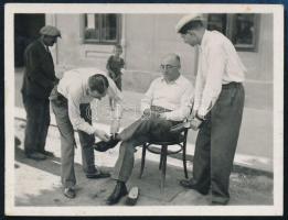 cca 1937 tréfából cipőfűzőjét kötik Lakner Artúrnak (1893-1944) rendezés közben, fotó, 4,5×5,5 cm