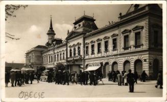 1943 Óbecse, Stari Becej; Szent István tér, Városháza, Janek Testvérek, Hubert Izidor üzlete, autóbusz, automobil, kerékpár. Ruzitska Mihály kiadása / square, town hall, shops, automobile, bicycle + 270. sz. Hajnal Cserkészcsapat Budapest (ragasztónyom / glue marks)