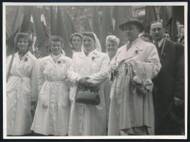 1954 KÖZÉRT feliratú köpenyben felvonuló hölgyek május elsején, hátoldalon feliratozott fotó, Neumann Miklós felvétele, 8×11 cm