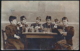 1910 Kártyázó, szivarozó fiúk és lányok katonai egyenruhában, Budapestről Temesvárra postázott fotólap, jelzés nélkül, egyik sarkában töréssel, 9×14 cm.