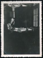 1941 Félixfürdő, Erdély, Bihar megye, postahivatal enteriőrje, Maksay Piroska postahivatalnok munka közben, hátoldalán feliratozott vintage fotó, bal alsó sarkában törésnyommal, 8,5x6,5 cm