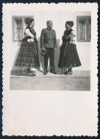 1940 Magyar határvadász tiszt népviseletbe öltözött hölgyek társaságában, fotó, hátoldalon albumba ragasztás nyomával, 8,5×6,5 cm