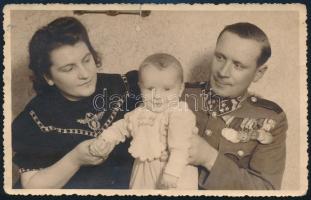 1942 Csendőrtiszt feleségével és kisfiukkal, számos kitüntetéssel dekorálva (Károly Vitézségi Érem, Károly-csapatkereszt, Felvidéki és Erdélyi emlékérem, stb.); fotólap, a hátoldalon feliratozva, kisebb szakadással, 13x8 cm