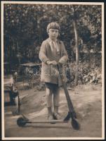 cca 1940 Kislány fa rollerrel, háta mögött gyerekautóval, fotó, 22×17 cm