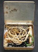 Kis bizsutétel láncokkal, medálokkal, éremmel, sárkányfejes karpereccel és egyéb testdíszekkel régi kalciumos fémdobozban