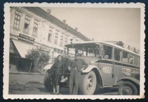 cca 1941 Tornalja (Tornaľa), Felvidék, a MÁVAUT Rimaszombat-Jolsva autóbuszjáratának busza a tornaljai főtéren, üzlettáblákkal (Danczinger Miklós cipőboltja, Dargay Dezső fodrászata, Kohn Jenő üzlete); fotó, a hátoldalon feliratozva, 9x6 cm