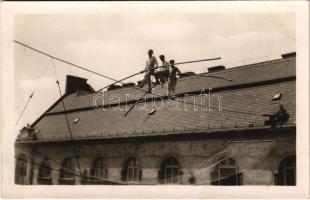 Kötéltáncosok két ház között kifeszített védőháló fölött, ketten széken viszik a harmadikat / rope dancers. photo