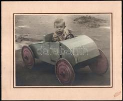 cca 1930 Kisfiú faautóban, kartonra kasírozott, színezett fotó Neuhausen kovásznai (Erdély) műterméből, szép állapotban, 17×22,5 cm