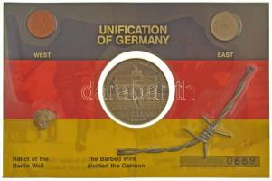 NDK 1983. 1pf Al + NSZK 1pf + 1989. "40 éves a Német Szövetségi Köztársaság 1949-1989 / Egyetlen fal sem választhat el örökre egy népet" fém emlékérem (40mm) egy közös "Németország egyesítése" sorszámozott angol nyelvű dísz kartonlapon a berlini fal és szögesdrót egy darabjával T:AU,XF a csomagolás sérült! GDR 1983. 1 Pfennig Al + FRG 1 Pfennig + "40 years of the Federal Republic of Germany 1949-1989 / No wall can separate people forever (Keine Mauer kann ein Volk ewig trennen)" metal commemorative medallion (40mm) on a "Unification of Germany" serial numbered English decorative cardboard sheet with a piece of the Berlin Wall and the barbed wire C:AU,XF damaged packing!