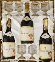 Tokaji aszú díszdoboz, össz. 3 palack bontatlan 1973-as évjáratú aszú (Hungarovin Monimpex) + 6 pohár készlettel: 5 puttonyos, 4 puttonyos, 3 puttonyos és 6 db Tokaj feliratos üveg pohár, m: 8 cm, jó állapotban. Selyemmel bélelt, egyik sarkánál kissé sérült karton díszdobozban