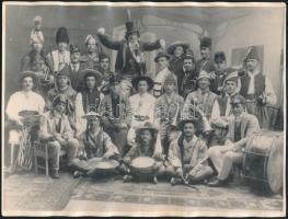 cca 1914 Csoportkép jelmezekbe öltözött zenekari tagokról, különféle hangszerekkel ,,megtűzdelve", 1 db vintage fotó, jelzés nélkül, ezüst zselatinos fotópapíron, a széle hullámos, 18x23,8 cm