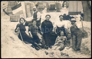 cca 1910 Strandolók a homokban, mögöttük strandszékek, fotólap, 9×13 cm