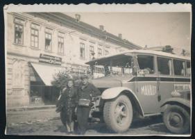 cca 1941 Tornalja (Tornaľa), Felvidék, a MÁVAUT Rimaszombat-Jolsva autóbuszjáratának busza a tornaljai főtéren, üzlettáblákkal (Danczinger Miklós cipőboltja, Dargay Dezső fodrászata, Kohn Jenő üzlete); a hátoldalon feliratozott fotó, 8x5,5 cm