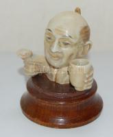 Régi, groteszk távol-keleti fejfigura kerámiából, fa talapzaton, magassága 6 cm