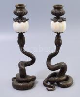 Tekergőző kígyó alakos bronz gyertyatartó pár, szájánál faragott csont gömb elemekkel. Jelzés nélkül, csont elemeken kopással, m: 25,5 cm /// A pair of serpentine-shaped bronze candle holders featuring intricately carved bone sphere elements at their mouths. The pieces are unmarked and exhibit some wear on the bone elements, with a height of approximately 25.5 cm.