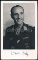 Wilhelm Batz (1916-1988) német Luftwaffe pilóta, repülő ász (237 légi győzelem), a Vaskereszt Lovagkeresztjének (tölgyfalombokkal és kardokkal) kitüntetettje autográf aláírása őt ábrázoló képen (későbbi előhívás), 20x12,5 cm / Autograph signature of Wilhelm Batz (1916-1988) German Luftwaffe pilot, fighter ace (237 aerial victories), recipient of the Knight's Cross of the Iron Cross (with Oak Leaves and Swords), on a photo (later copy), 20x12.5 cm