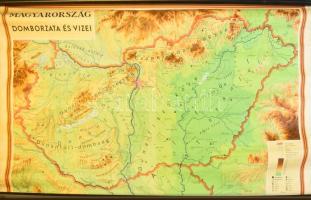 [Térkép] Magyarország domborzata és vizei. Iskolai falitérkép. Mértéke: 1 : 350,000. (1979) Budapest, 1979. Kartográfiai Vállalat. Színes térkép, mérete 995x1490 mm egy 1120x1640 mm méretű térképlapon. Összesen 2000 példányszámban megjelent, a Művelődési Minisztérium által engedélyezett iskolai falitérkép, lajstromszáma: 1979 010169-05. Az adatok szerkesztése 1978. április 30-án zárult. Domborzati térképünk hegy- és vízrajzi elemeket, válogatott településhálózati részleteket, valamint ásványi lelőhelyeket ábrázol. A színkódolt hegyrajzi részletek esetében a hegységek, hegycsúcsok az országhatáron túl is magyar nyelvűek, így a Selmeci-hegység turizmustörténetileg kitüntetett szerepű hegycsúcsa, a Szitnya, valamint mellette a Jávoros is magyar megnevezéssel szerepel, ugyanez elmondható az Erdélyt szegélyező szigethegység tagjairól (Réz-hegység, Király-erdő, Bihar). Térképünk a hazai bányászat jelentős felfutásának idején készült, így a mecseki, dorogi, salgótarjáni, bükkaljai szénkincset is feltünteti, a Bakony és a Vértes bauxit-, Göcsej és az Alföld kőolaj- és földgázkincsével együtt. Egyes települések mellett tengerszint feletti magasságuk is szerepel. Zavaró közlekedési részleteket nem tartalmazó térképünk kiválóan alkalmas a földrajzi tájegységek (Őrség, Bakonyalja, Zselicség, Ormánság, Bugac, Torontál, Kis-Sárrét, Nyírség, Tiszahát, Rétköz, Aggteleki-karszt), illetve folyóink és csatornáink tanulmányozására. Térképünkön felül, középen apró javítások, hátoldalán illesztések. Jó állapotú térképlap, vászonra kasírozva, alsó és felső térképléccel.