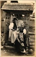 Körösfő, Izvoru Crisului (Kalotaszeg, Tara Calatei); La poarta / Körösfői faragott kapuban fiatal pár, erdélyi folklór / Transylvanian folklore, carved wooden gate. Foto orig. J. Fischer 1931. (EK)
