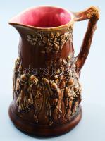 Sarreguemines judaika szukkoti boroskancsó. cca 20. sz. eleje, mázas öntött fajansz, körben a szukkoti mulatság plasztikus ábrázolásával, kívül csokoládébarna, belül pink színű mázzal, szőlőtörzset imitáló füllel, jelzett, hibátlan, mázrepedéssel, m: 24 cm /// Sarreguemines Judaica Sukkot wine pitcher. Circa early 20th century, glazed molded faience, with a relief depiction of the Sukkot celebration around the body. Forest green glaze on the exterior, turquoise glaze on the interior, handle shaped like a grapevine trunk, marked, flawless condition, height: 24 cm