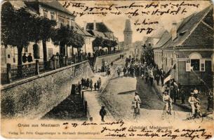 Medgyes, Mediasch, Medias; Forkeschgasse. Verlag Fritz Guggenberger / felvonulás, utcakép, városkapu, biciklisták / procession, street, gate, cyclists + "BRASSÓ - BUDAPEST 15. SZ." vasúti mozgóposta bélyegző (gyűrődések / creases)