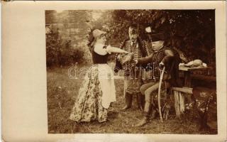 Hagyományos magyar viseletbe öltözött nő tölt italt két magyar férfinak / Woman dressed in traditional Hungarian costume pouring drink to Hungarian men. photo (kis szakadás / small tear)