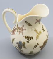 Zsolnay aranyhal mintás kancsó. cca 1885, magastüzű mázakkal festett finomfajansz, aranykontúrozott aranyhal mintákkal díszítve. Alján jelzett: máz alatti kobaltkékkel családi jegy és Made in Hungary felirat. Repedezett mázzal, kopással, m: 15 cm /// A Zsolnay-család tagjai keleti utazásaikról küldték haza az ott megismert kínai porcelánokat, kezdetben ezeket igyekeztek utánozni a pécsi Zsolnay gyárban. A jelen aukción szereplő kancsó is kínai előképeket követ: sajátos felülnézeti perspektívából úszkáló aranyhalakat és hínárnövényeket ábrázol, aranykontúrozással. Rendkívül ritka gyűjtői darab.