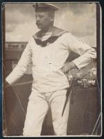 1916 Dunai Flottila. S.M.S. Samson matróza 9x12 cm  // Danube Fleet,  S.M.S. Samson Black-and-white photograph of a seasoned sailor standing on the bridge of a ship. In the background, laundry hangs on lines and a man is leaning over a bucket. The ship?s name cannot be made out on his cap, but the name Bagomir Krause and the date 1916 are written on the back.