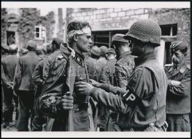 cca 1944 Robert Capa (1913-1954) (eredeti neve Friedmann Endre) magyar - francia fotóriporter felvétele (fogságba esett német katonát motoz egy amerikai katona), 1 db modern nagyítás, jelzés nélkül, Fotó újság archívumából, 15x21 cm