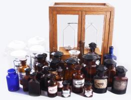 cca 1850-1950 Patika hagyaték. Patikai mérleg üvegezett oldalú ajtós vitrinben 42x40x22 cm, fiókjában mérlegsúlyok. Hozzá különböző korszakokból 25 darab patikai üveg és tégely, közte 2-3 sérült darabbal. /// ca. 1850-1950 Pharmacy estate. Pharmacy balance in a glazed-door cabinet (42×40×22 cm), with balance weights in the drawer. Together with 25 pharmacy bottles and jars from different periods, including 2-3 damaged pieces. /// KIZÁRÓLAG SZEMÉLYES ÁTVÉTEL, NEM POSTÁZZUK! / ONLY PERSONAL COLLECTION AT OUR OFFICE!