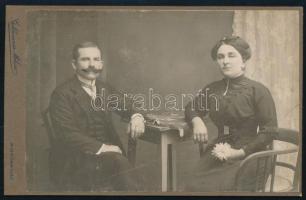 cca 1910 Elegáns pár portréja, kabinetfotó Goldmann Miksa kiskunhalasi fényképészeti és festészeti műterméből, szecessziós verzóval, 10,5x16,5 cm. Ritka!
