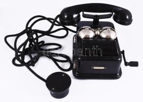 cca 1924 Standard Villamossági RT."LB 24" tárcsázós telefon, kopással, 21x25 cm /// "Az első - falon és asztalon egyaránt alkalmazható - nagy példányszámban gyártott, helyi telepes, fémdobozos LB készülék. Az alaplemezen az induktor, az indukciós tekercs és a csatlakozó szorítók találhatók. A csengő, az önműködő átkapcsoló rúgói a készülékházon belül; a csengőcsészék, az önműködő villa szerkezete, valamint az induktorkar kívül található. Az alkatrészeket cserélhető módon csavarokkal rögzítették. A készülék 5 erű zsinórral csatlakozik a dugaszkapcsolóhoz (2 a vonalhoz, 2 a telephez, az 5. vezeték az esetleges külön pótcsengőhöz vezetett). A helyi telepet különálló teleptartó dobozba helyezték."