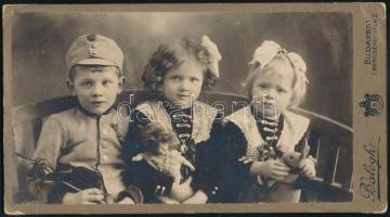 1912 Gyerekek (két kislány és egy kisfiú) portréja, a kisfiú katonai egyenruhában, keményhátú fotó Balogh budapesti műterméből, sarkain kissé sérült, 11,5x20,5 cm