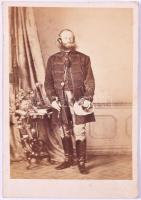 ca 1860 Podmanini és aszódi báró Podmaniczky Frigyes (1824-1907) író, politikus, Fővárosi Közmunkák Tanácsának alelnökről készült vizitkátya méretű fotó korabeli feliratozással 6x9,5 cm   Az 1860 körüli időszak a magyar arisztokrácia esetében még a vizitkártya-fotó (carte de visite) műfajának kezdeti szakasza. Ekkor: a fényképezés még drága és kevéssé elterjedt, nem minden közszereplőről készült sorozatban terjesztett portré, a felvételek nagy része nem maradt fenn, vagy sérült. Podmaniczky Frigyes ikonográfiája szűk. Noha "Budapest vőlegényeként" közismert, kevés igazán korai fiatalkori fénykép ismert róla. A legtöbb ábrázolás későbbi, 1870-1890 közötti, már a városépítő "nagy öreg" szerepében mutatja. Az 1860 körüli portré még a nagy városformáló korszak előtti Podmaniczkyt ábrázolja.  Amikor 1873 után a főváros rohamos fejlődésnek indult, Podmaniczky a Fővárosi Közmunkák Tanácsának alelnökeként gyakorlatilag felügyelte az Andrássy út kialakítását, részt vett a Nagykörút szabályozásában, döntő szerepe volt a Sugárút, a közparkok és közlekedési tengelyek megtervezésében. Soha nem nősült meg. Kortársai tréfásan - de találóan - nevezték el "Budapest vőlegényének", míg mások családot alapítottak, ő egy várost nevelt fel. Ez az 1860 körüli fénykép még azt az embert mutatja, aki a reformkor és a kiegyezés közötti átmenetben áll, tele van tervekkel, de még nem sejti, hogy fél évszázadon át Budapest arculatát fogja meghatározni.