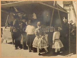 1939 Tarjánné Dvihally Anna (1907-1982): "Bucsuban", fotó kartonon, "B. S. E. Fotokiállítás 1939" címkével, a hátoldalon feliratozva, foltos, sérült, részben hiányos kartonnal, a fotó felületén karcolásokkal, sérülésekkel, 22x30 cm, karton: 42x47 cm