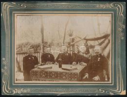 cca 1910-1915 Asztalnál borozó csendőrök (tiszthelyettesek), Katonai Jubileumi Kereszt kitüntetéssel, egyikükön tábori csendőr jelvénnyel, mögöttük gramofonnal. Kartonra kasírozott fotó, szecessziós kartonon, 17,5x23 cm