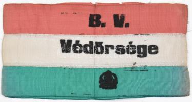 XX. század közepe "B. V. Védőrsége" feliratú karszalag, a szöveg alatt feltehetőleg koronás nemzeti kiscímerrel, (B.V. = Büntetés Végrehajtás, vagy Budapest Város??), sérült, 10x20 cm