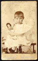 cca 1900 Kislány babával, keményhátú fotó Anner József besztercebányai műterméből, kopásnyomokkal, 10,5×6,5 cm / Banská Bystrica, vintage photo with faults